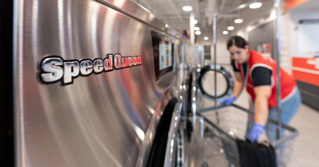 close up of machine with employee inside laundromat